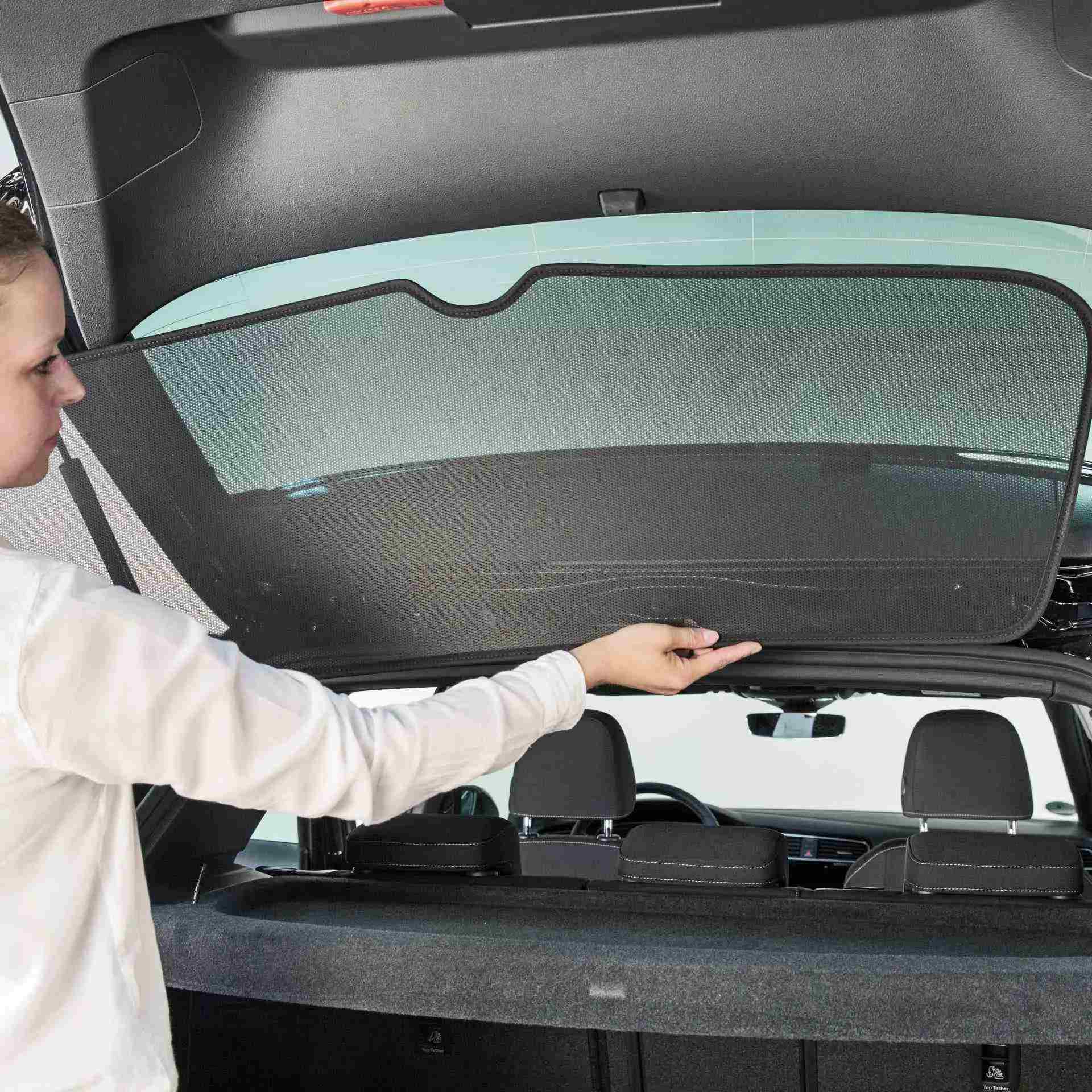 a woman attacheds a sun screen at the rear window