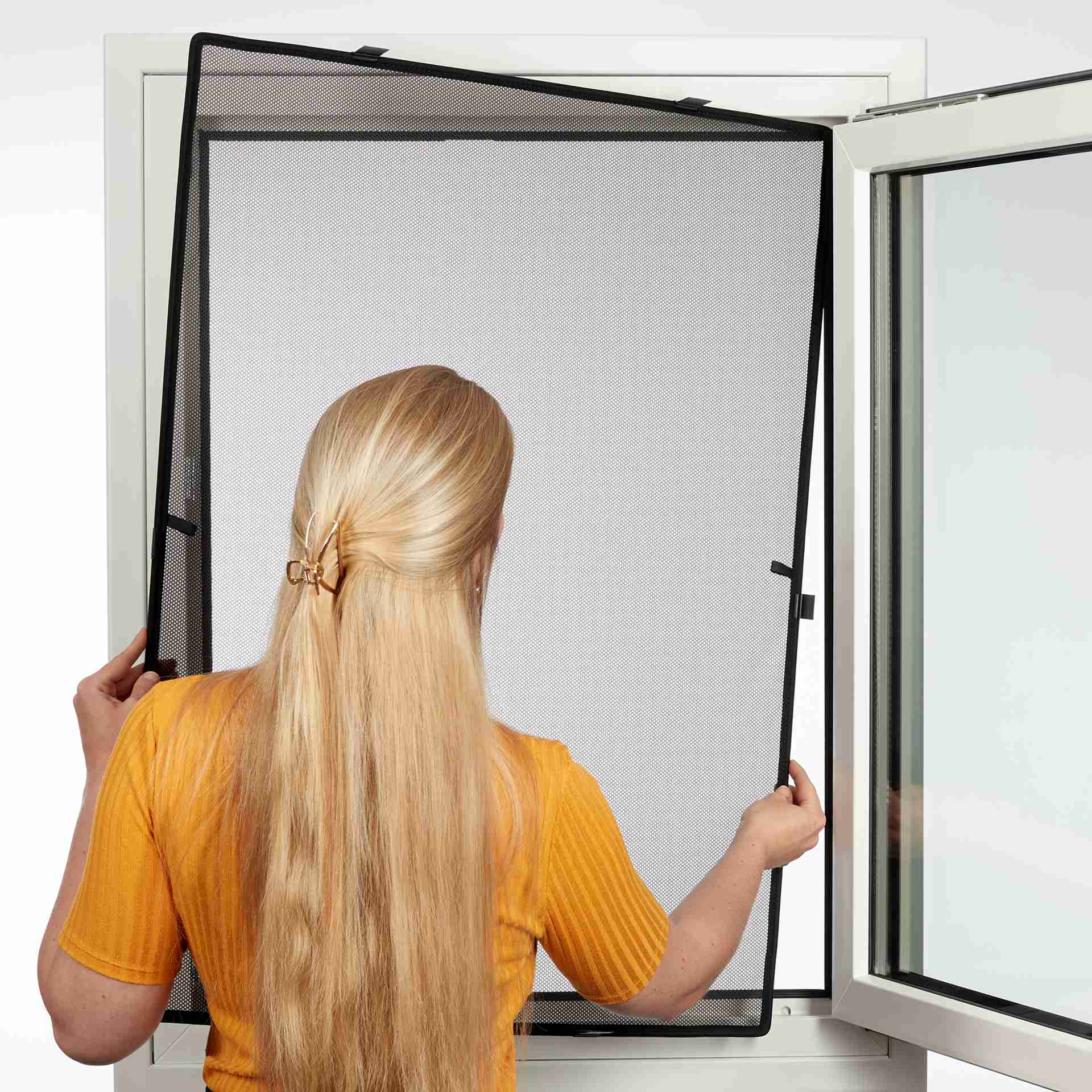 eine Frau hält den WinClip Style an ein Fenster