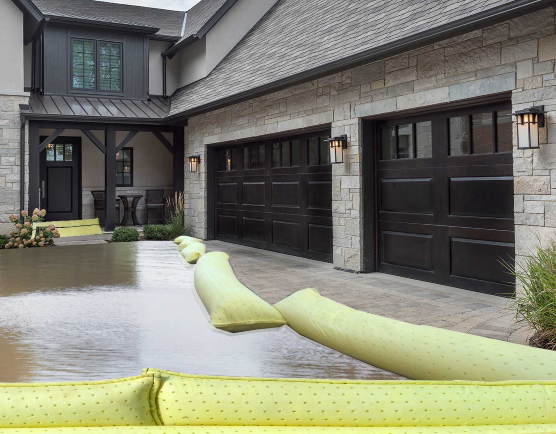 Vor einem Haus liegen Wasserschutzschläuche als Barriere vor Hochwasser aus