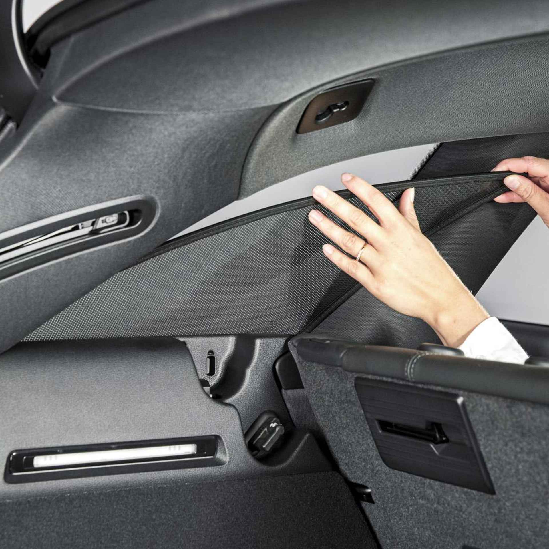 a woman attaches a sun screen at the side window