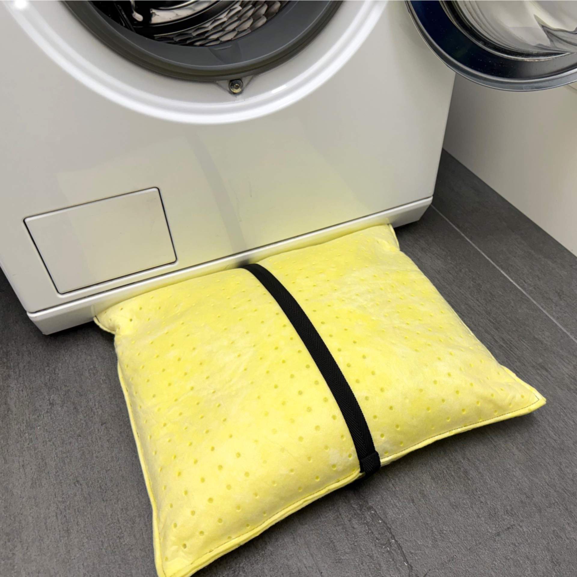 ein Wasserschutzkissen liegt vollgesogen vor einer Waschmaschine