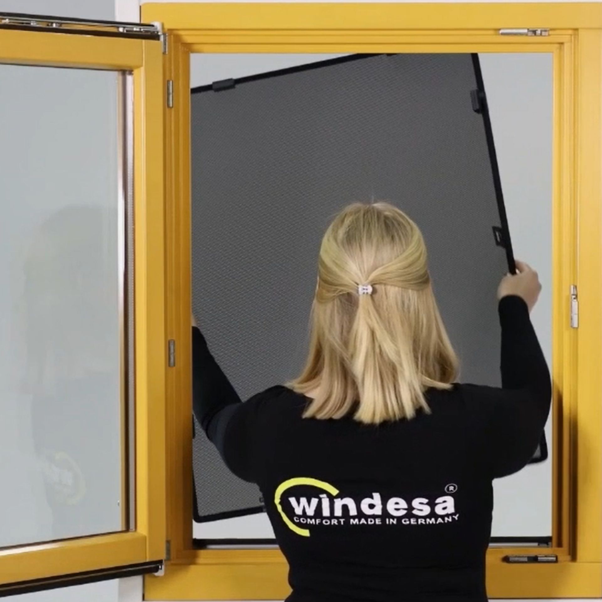 eine Frau installiert einen WinClip Multi in ein Holzfenster